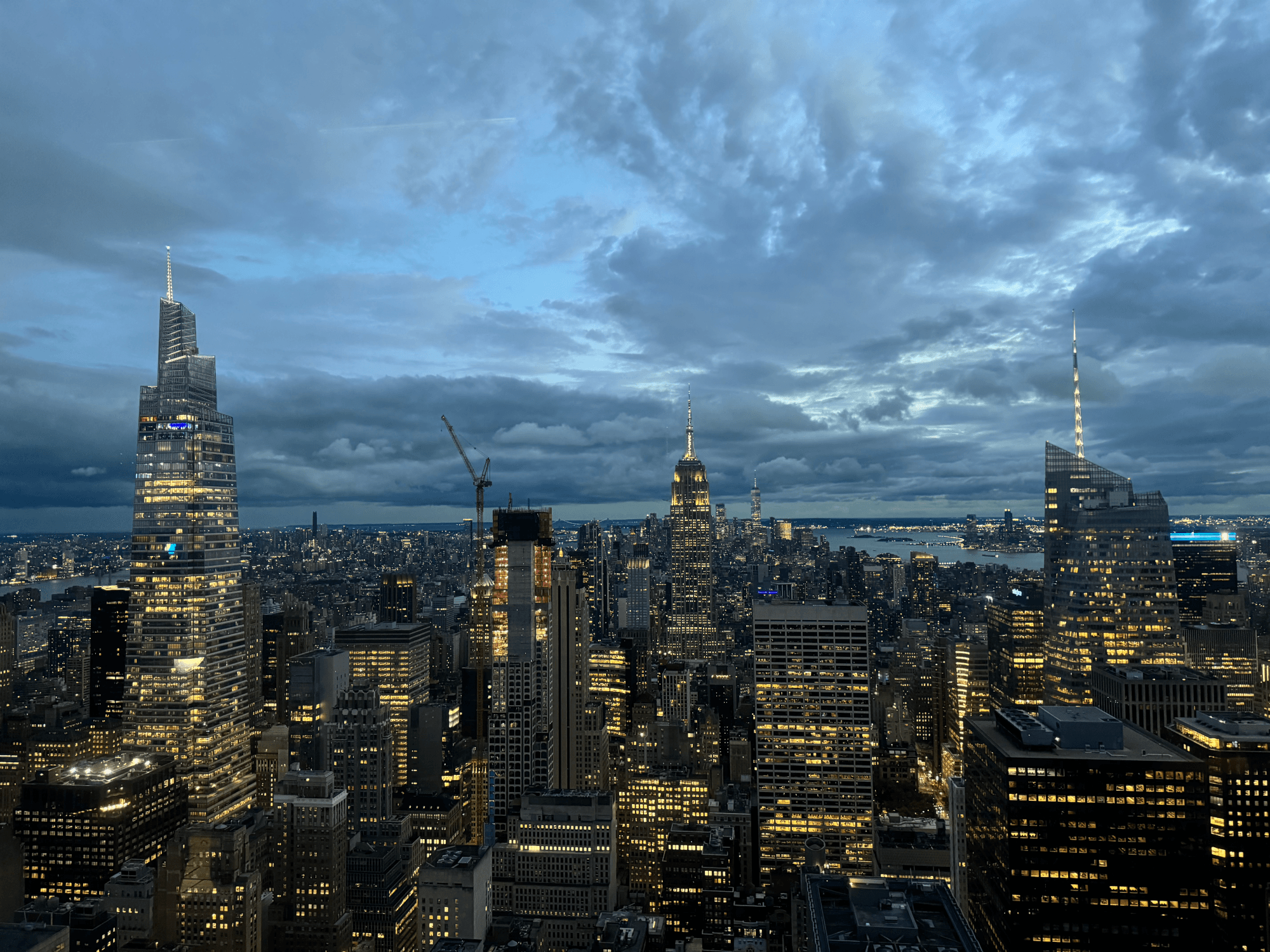 Picture of the New York City skyline at dusk. The building lights are already on, but the sky isn't dark yet.
